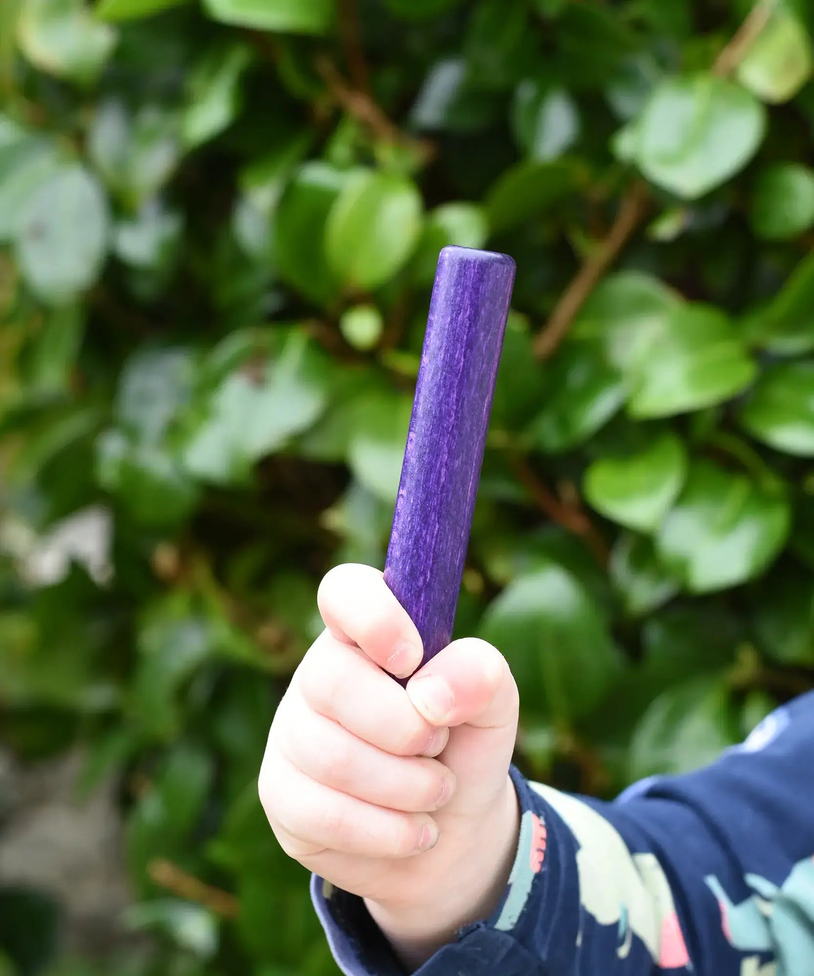 Child holding the purple pole from the Bajo Puzzle Stacker Tower in his hand. 