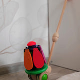 Bajo rainbow flower push along toy learning against a grey cupboard