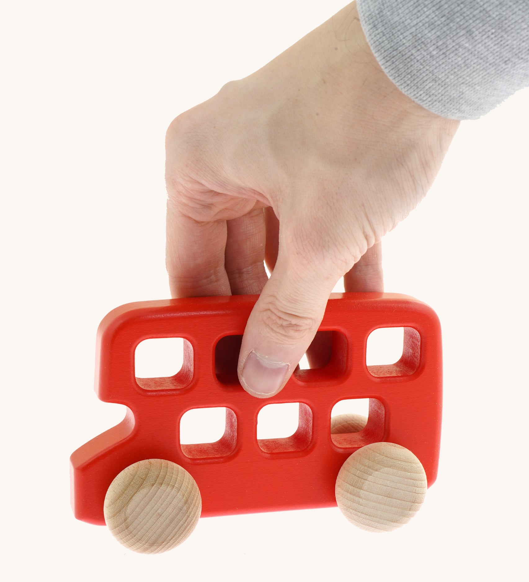 An adult hand holding the top of the Bajo woode red double decker bus available at Babipur showing scale