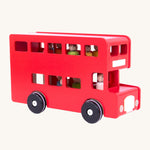 An image from the side of the Red Bajo London Bus, with colourful wooden peg dolls inside, on a cream background