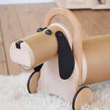 Bajo Ride On Wooden Dog with 4 wheels, working steering, a long nose and black felted ears and button eyes.