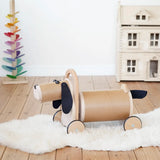 Bajo Ride On Wooden Dog with 4 wheels and black felt tail and ears, a sit on barrel shaped sit on toy with working steering, in the Babipur playroom.