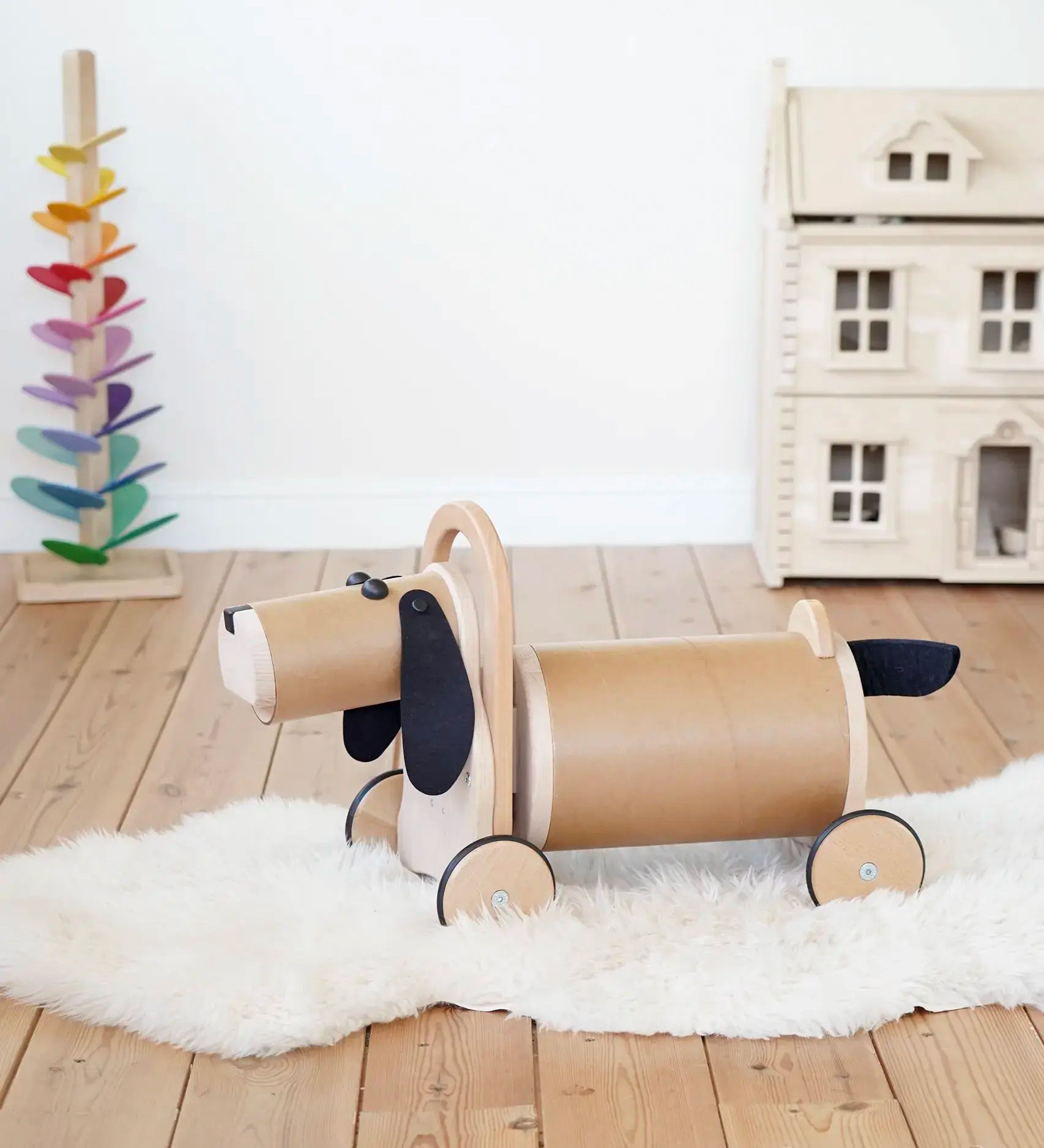 Bajo Ride On Wooden Dog with 4 wheels and black felt tail and ears, a sit on barrel shaped sit on toy with working steering, in the Babipur playroom.
