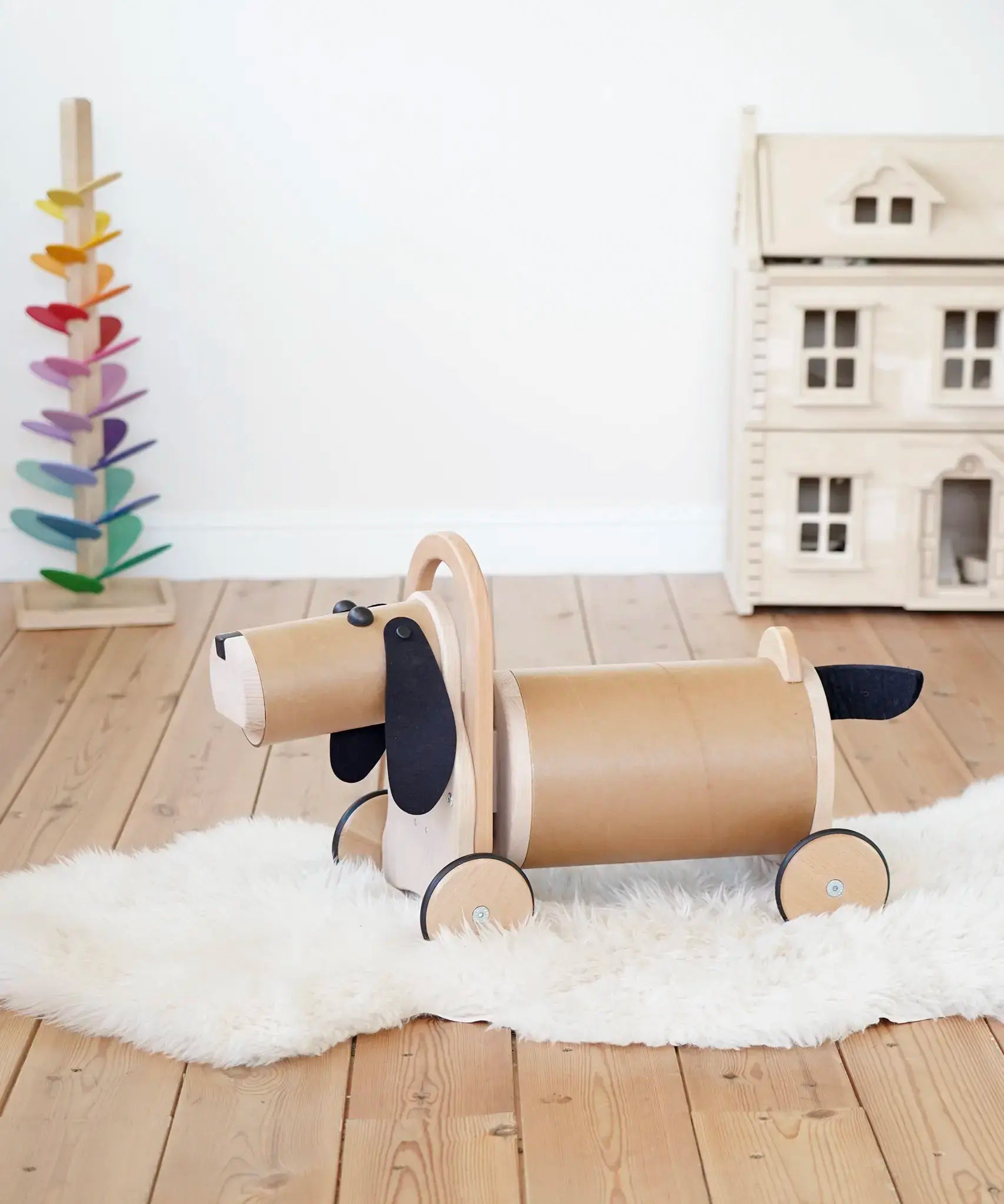 Bajo Ride On Wooden Dog with 4 wheels and black felt tail and ears, a sit on barrel shaped sit on toy with working steering, in the Babipur playroom.