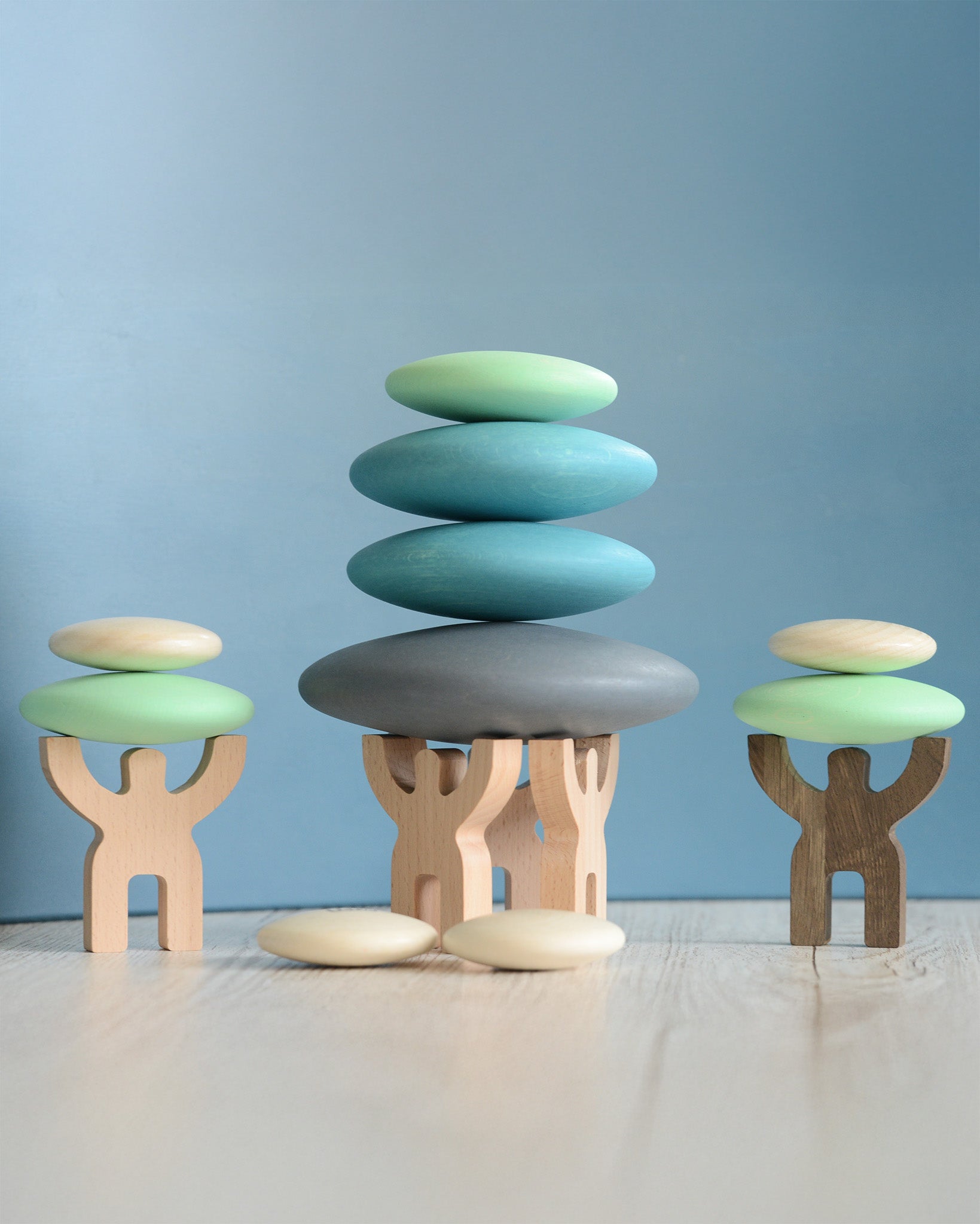 Bajo mendelsons holding ten blue and white wooden circular pebbles from Bajo, smooth and tactile, stacking toys sold at Babipur.