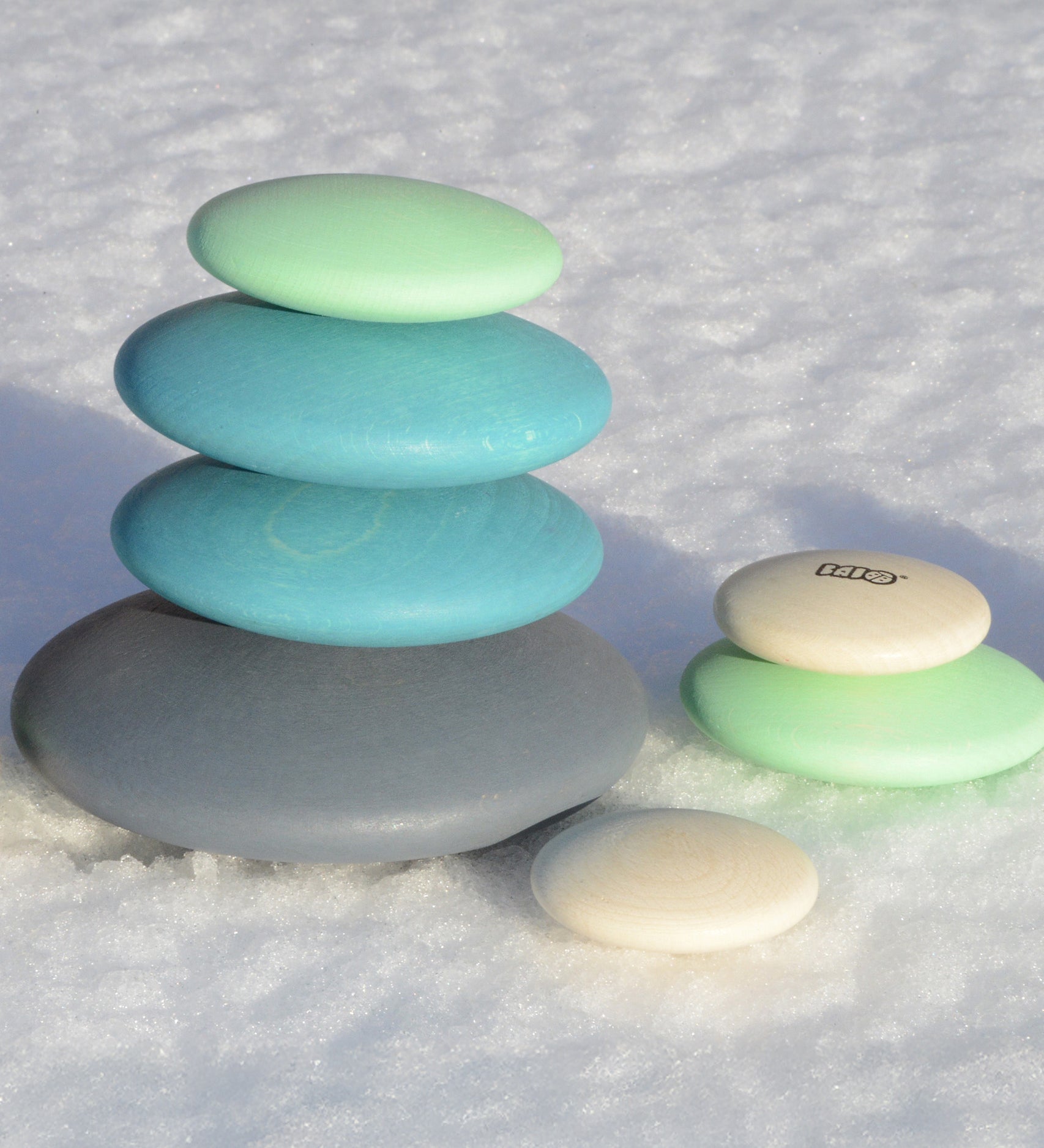 Set of 10 smooth, tactile wooden circular pebbles by Bajo in shades of blue and white, for stacking or small world play, available at Babipur.