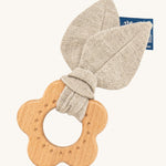 The Hempions Flower Baby Teether is an adorable baby teething toy made from natural hemp textile and solid wood, in the shape of a flower. The image shows the wooden flower teething ring with a light grey/beige hemp leaf fabric attached to it, on a cream background