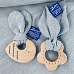 The Hemptons Flower and Bee baby teething rings, next to each other on a grey hemp fabric