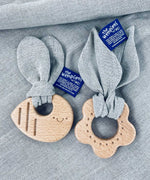 The Hemptons Flower and Bee baby teething rings, next to each other on a grey hemp fabric
