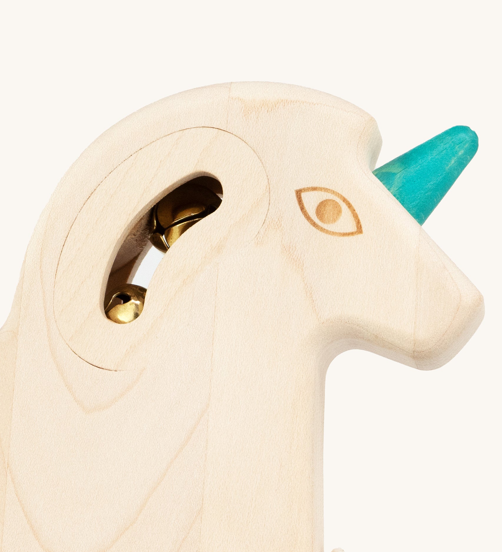 A closer look at the gold coloured bells inside the unicorn head, and the turquoise horn on the front of the unicorn head. The image is on a cream background
