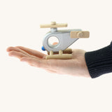 An adult hand holding the Bajo wooden police helicopter available at Babipur showing scale of the vehicle