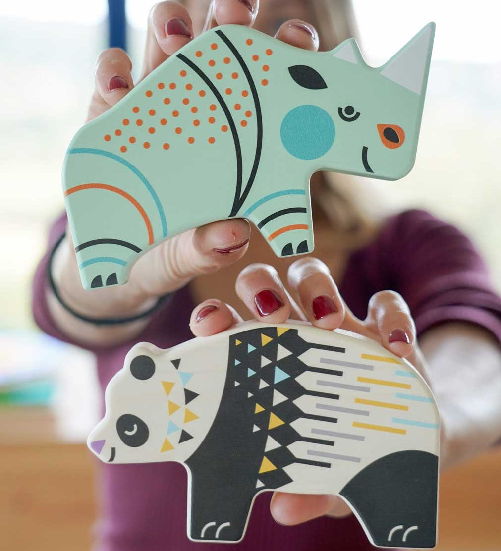 A member of the Babipur team holding up a Bajo rhino and panda Endangered Animals wooden toy figures up to the camera. These heirloom quality toys by Bajo are part of a wide range of wooden toys available here at Babipur.