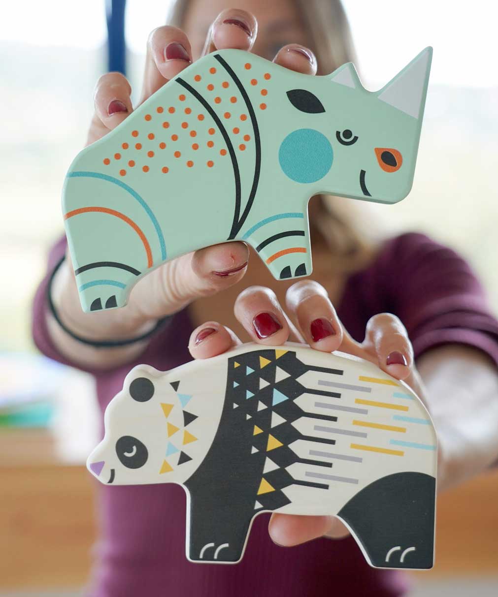 A member of the Babipur team holding up a Bajo rhino and panda Endangered Animals wooden toy figures up to the camera. These heirloom quality toys by Bajo are part of a wide range of wooden toys available here at Babipur.