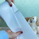 Hands tearing a paper liner by Bambinex, designed to catch poo for reusable nappies, for sale at Babipur.