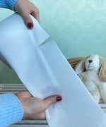 Hands tearing a paper liner by Bambinex, designed to catch poo for reusable nappies, for sale at Babipur.