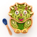 Eco Rascals Dinosaur Bamboo Suction Plate, filled with kiwi slices to look like a triceratops and blue silicone and bamboo baby spoon.