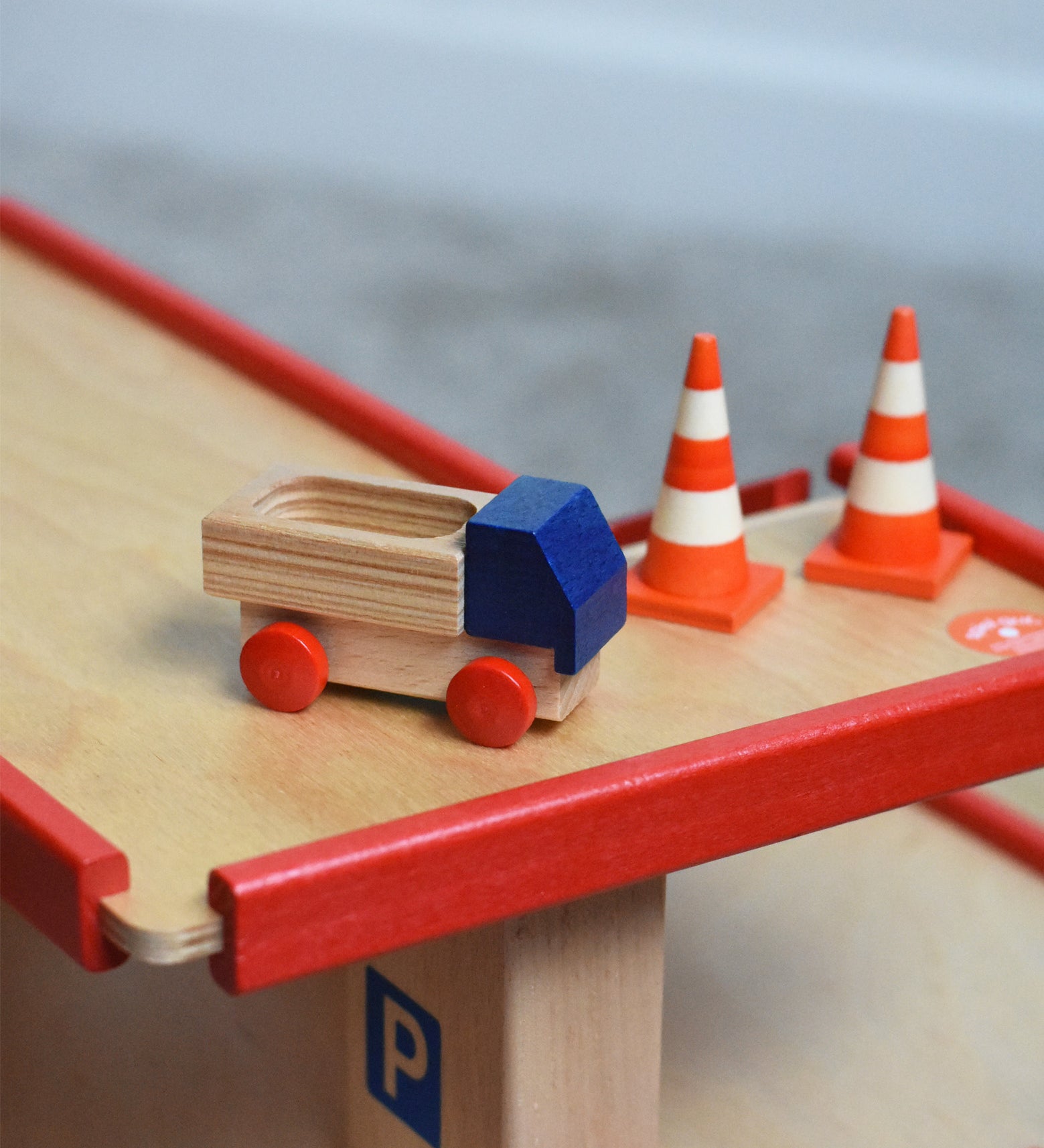 A mini wooden toy delivery lorry on top of the wooden toy multi-story car park by Beck-Holzspielzeug