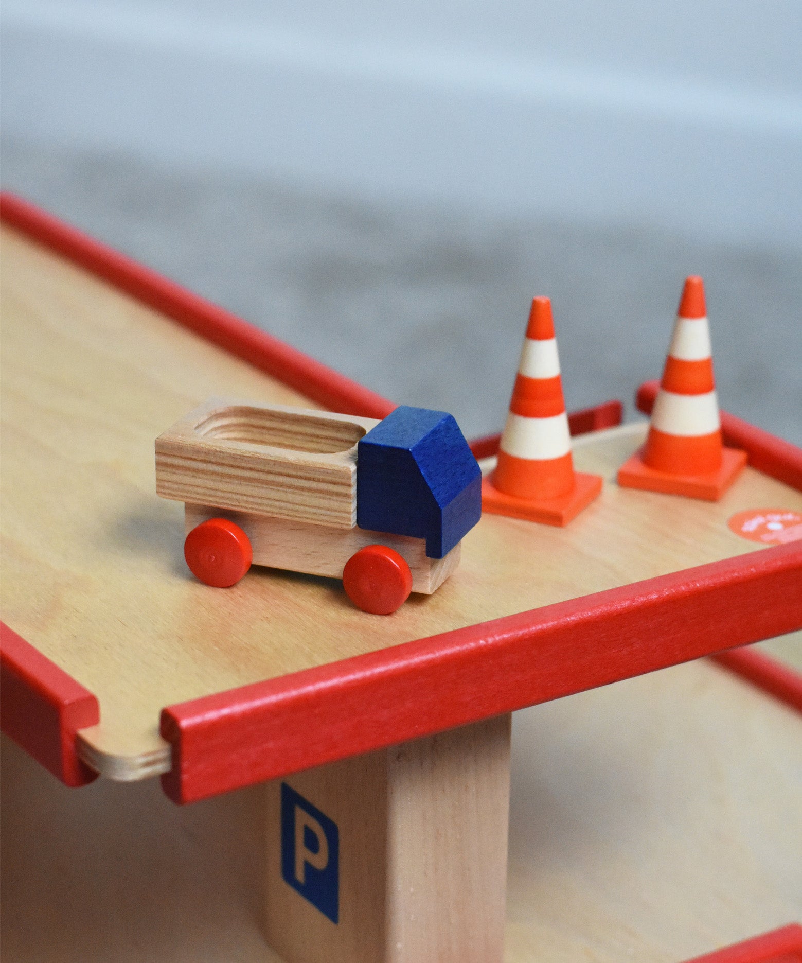 A mini wooden toy delivery lorry on top of the wooden toy multi-story car park by Beck-Holzspielzeug