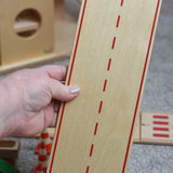 A person holding a straight piece of the wooden toy road set by Beck-Holzspielzeug.