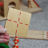 A person holding the T Junction piece of the wooden toy road set by Beck-Holzspielzeug.