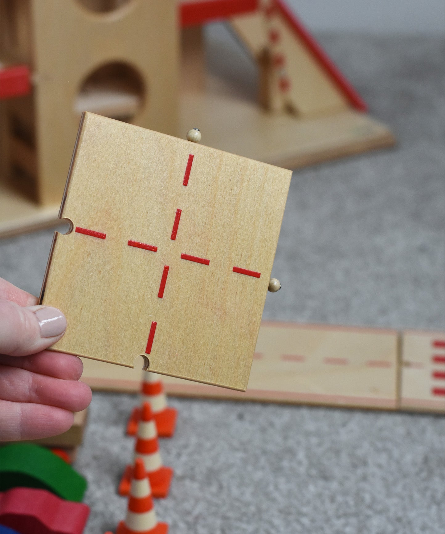 A person holding the T Junction piece of the wooden toy road set by Beck-Holzspielzeug.