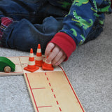 A child blocking the wooden toy road with mini wooden traffic cones by Beck-Holzspielzeug