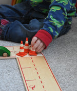 A child blocking the wooden toy road with mini wooden traffic cones by Beck-Holzspielzeug