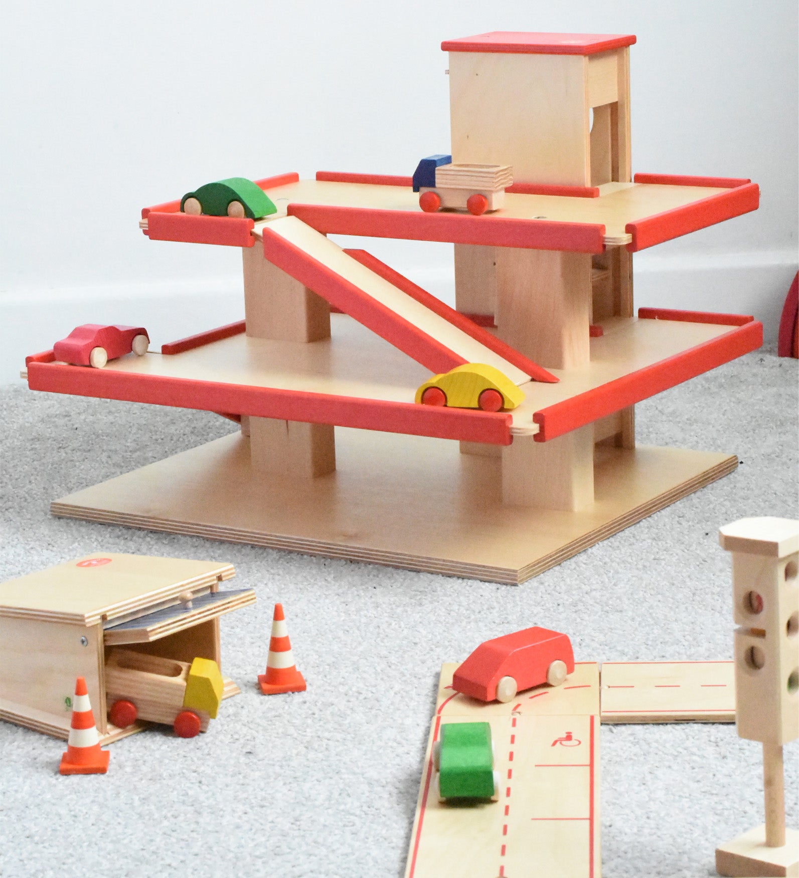 The multi-storey car park wooden toy by Beck-Holzspielzeug, with mini wooden toy cars, and surrounded by the Beck wooden road set and parking garage.