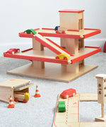 The multi-storey car park wooden toy by Beck-Holzspielzeug, with mini wooden toy cars, and surrounded by the Beck wooden road set and parking garage.