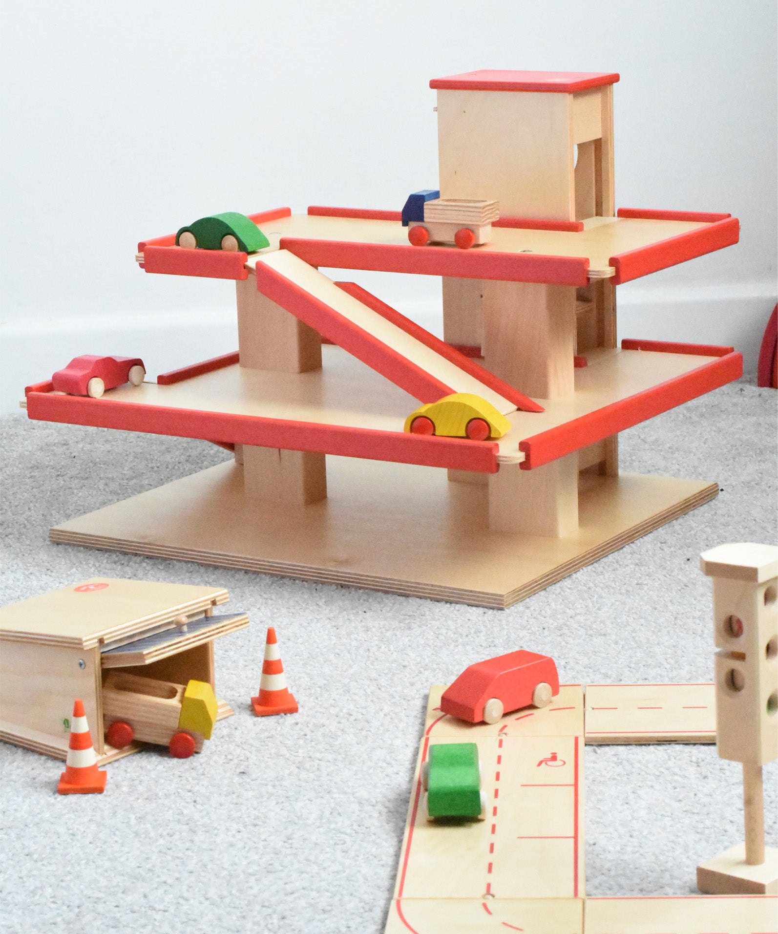 The multi-storey car park wooden toy by Beck-Holzspielzeug, with mini wooden toy cars, and surrounded by the Beck wooden road set and parking garage.