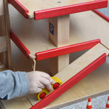 A child pushing a wooden toy car up the wooden multi-storey car park by Beck-Holzspielzeug