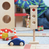 The wooden toy traffic lights by Beck-Holzspielzeug, set in a small-world city play scene with toy cars and traffic cones. 