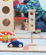 The wooden toy traffic lights by Beck-Holzspielzeug, set in a small-world city play scene with toy cars and traffic cones. 