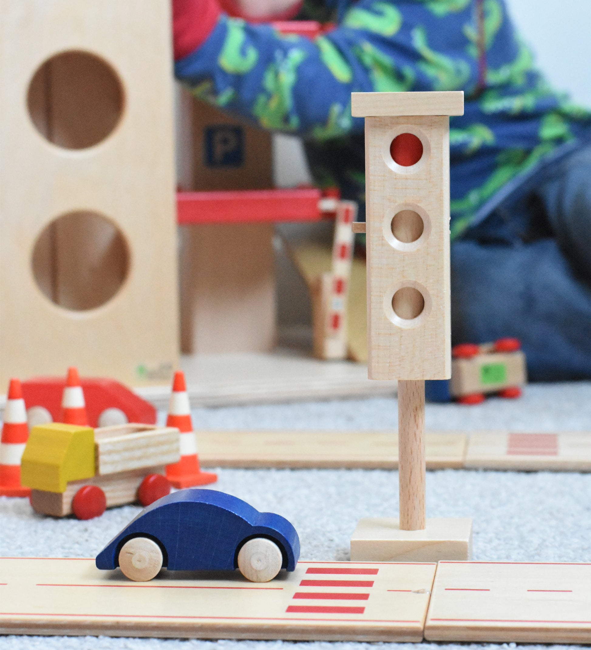 The wooden toy traffic lights by Beck-Holzspielzeug, set in a small-world city play scene with toy cars and traffic cones. 