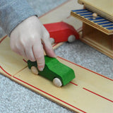 A child pushing a little wooden toy passenger car along he wooden toy road system by Beck-Holzspielzeug.
