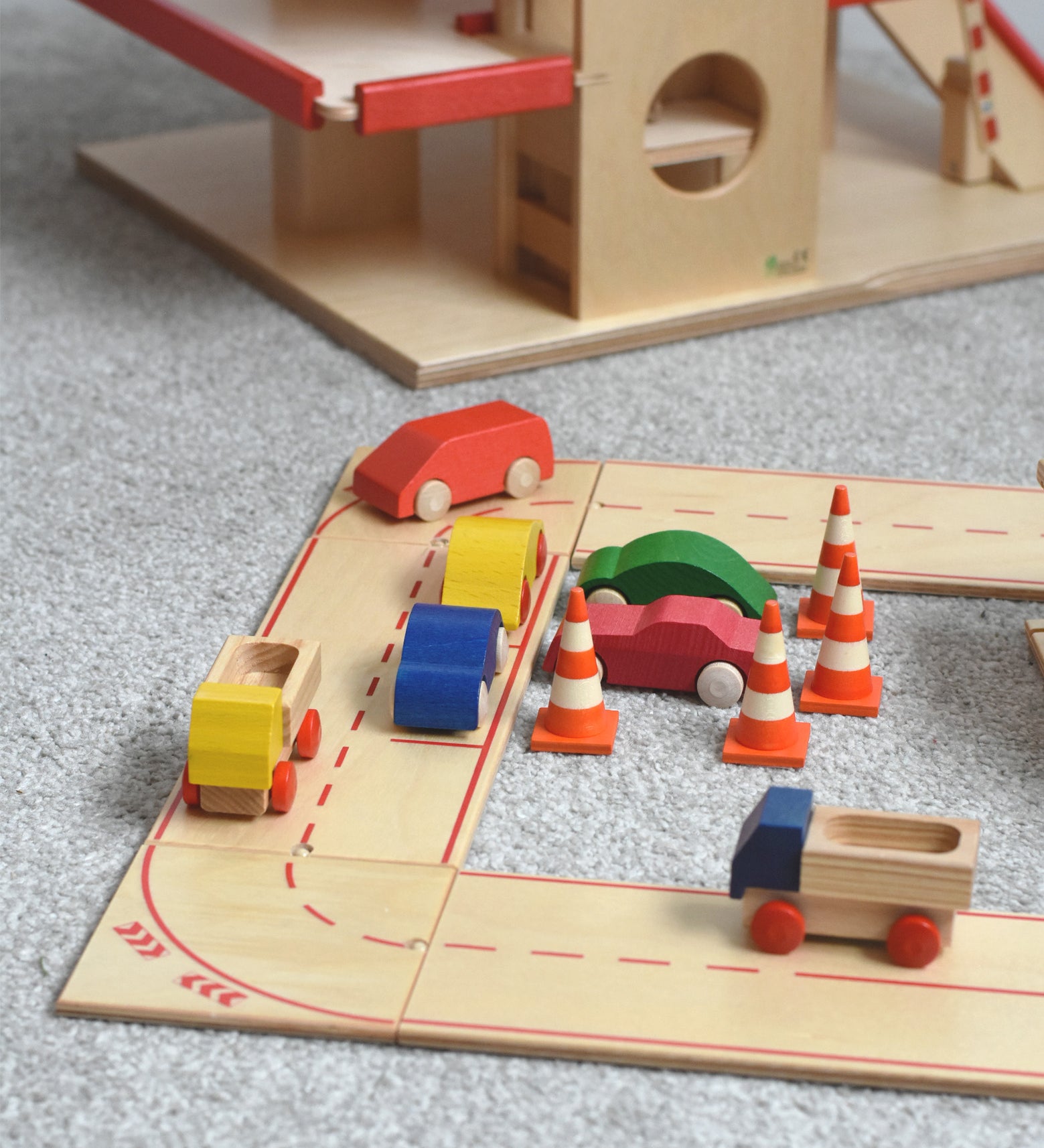 The wooden road and city system playset by Beck-Holzspielzeug, set up in a small-world town play scene with toy cars and traffic cones. 