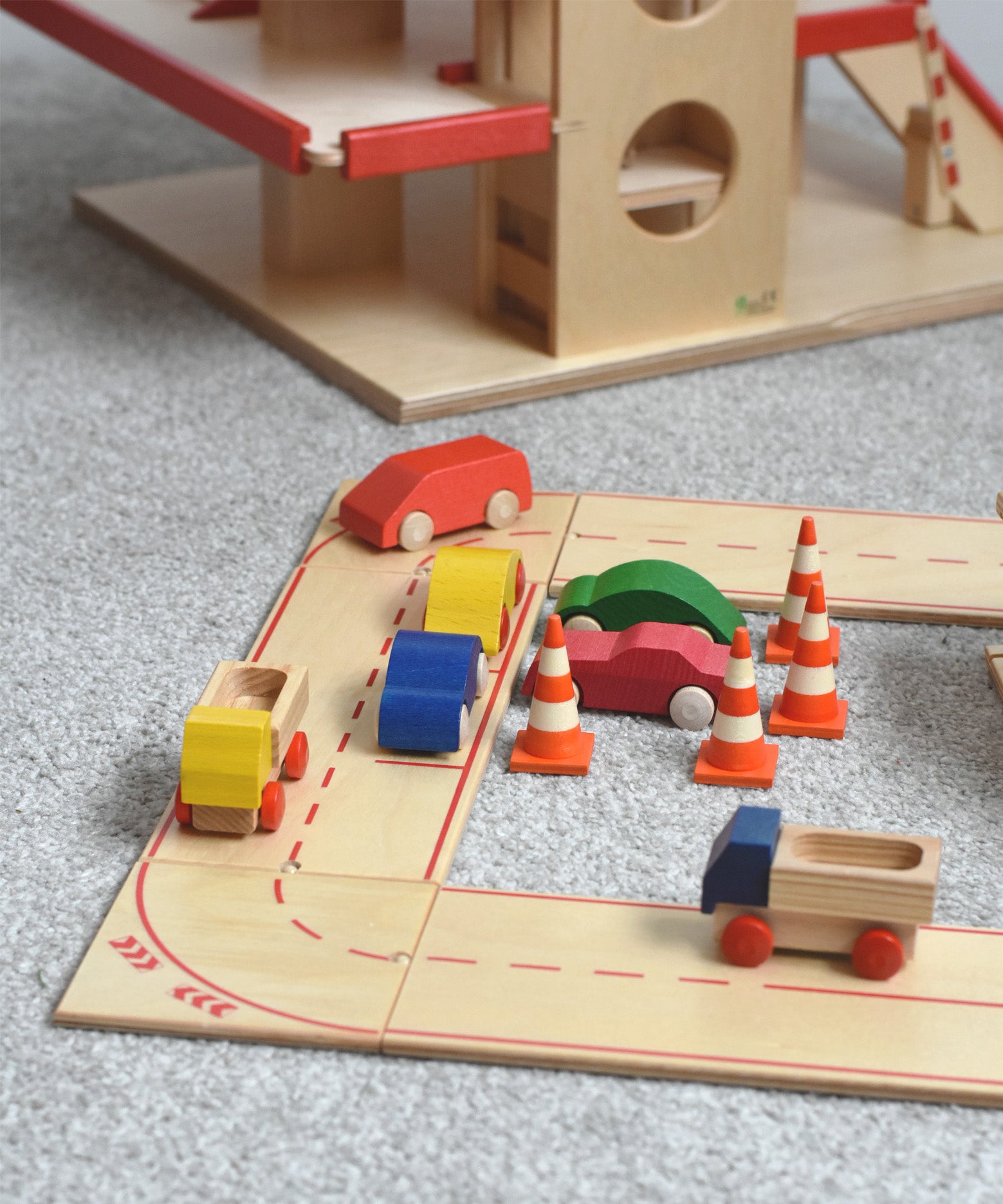 The wooden road and city system playset by Beck-Holzspielzeug, set up in a small-world town play scene with toy cars and traffic cones. 