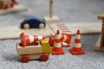 A mini wooden toy delivery lorry by Beck-Holzspielzeug, carrying wooden toy traffic cones.