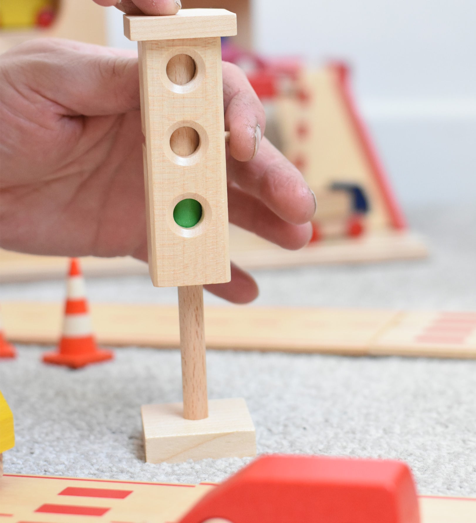 The wooden mini traffic light toy by Beck-Holzspielzeug, being switched to a green light for small world city play. 