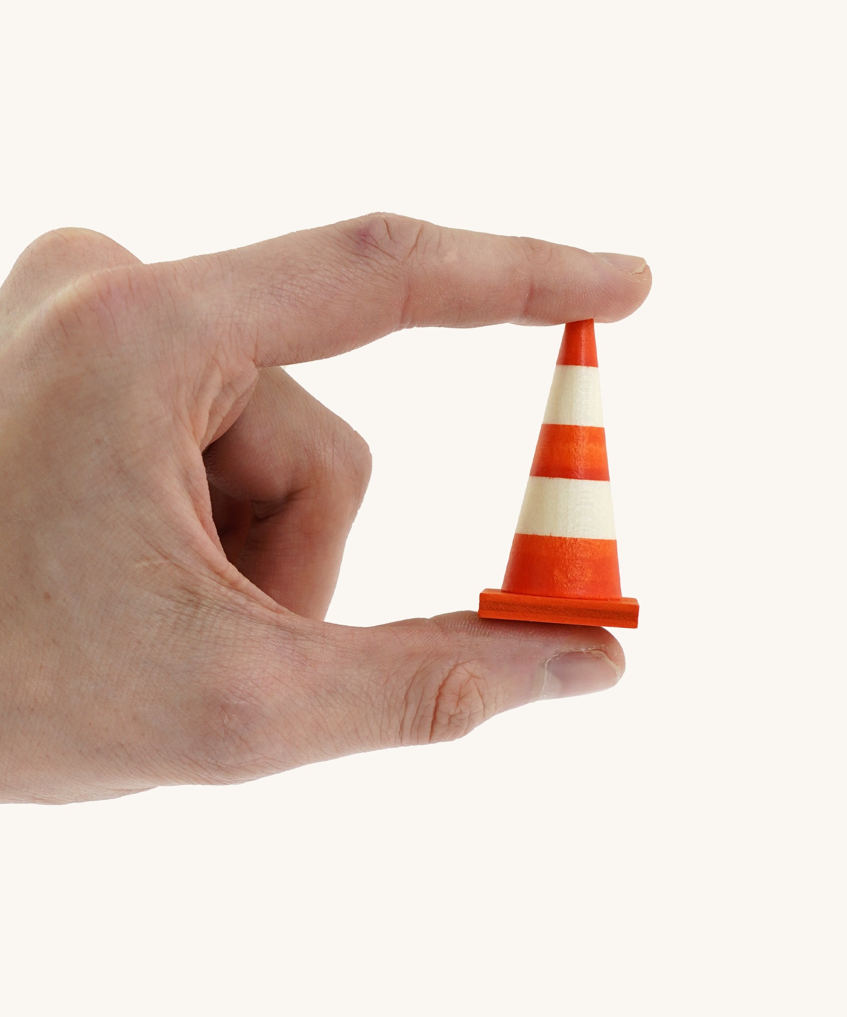 An adult hand holding the Beck mini wooden traffic cone available at Babipur showing scale