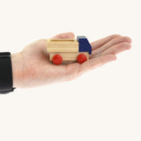 An adult hand holding the Beck wooden lorry toy in blue available at Babipur showing scale