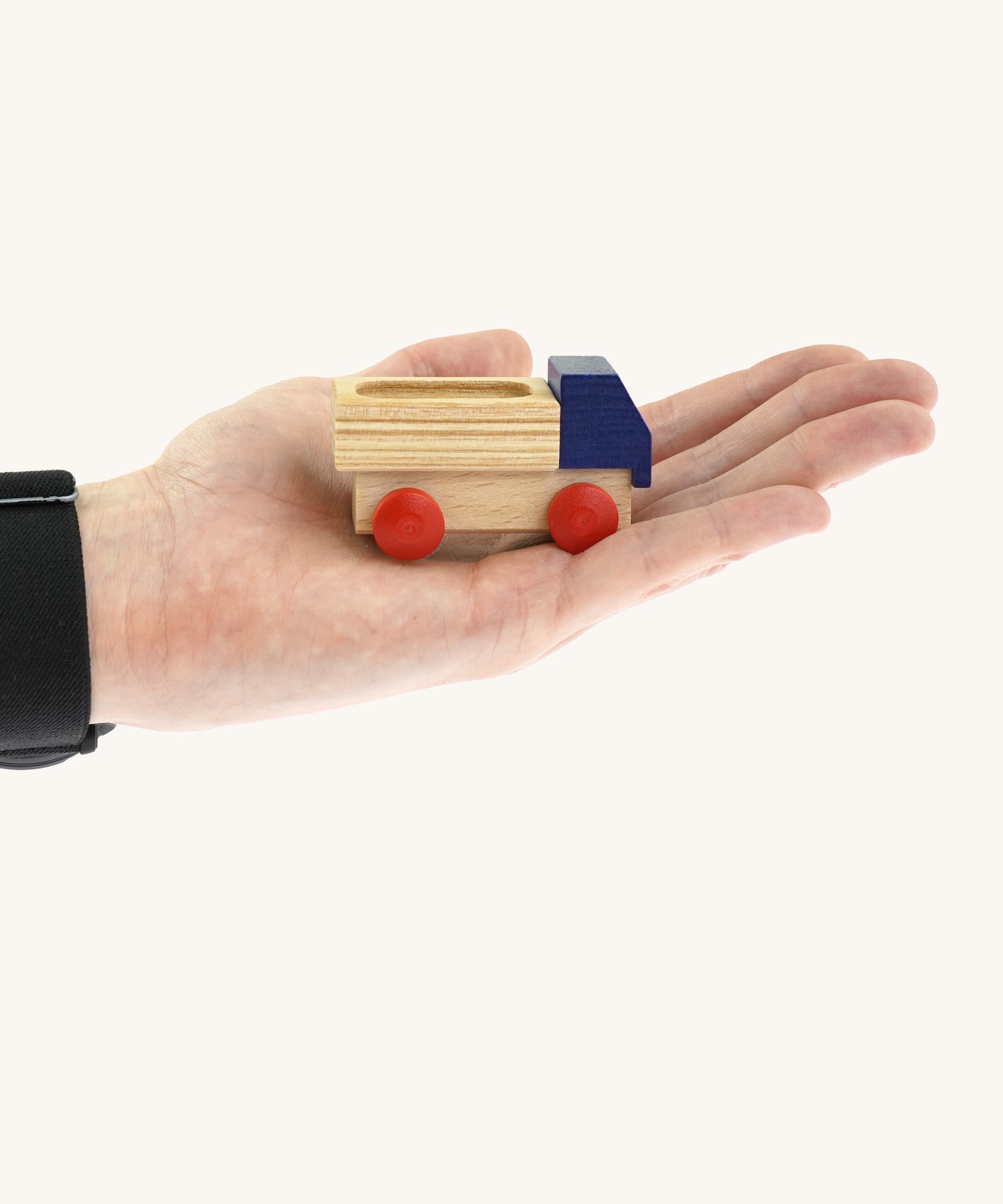 An adult hand holding the Beck wooden lorry toy in blue available at Babipur showing scale