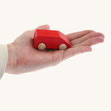 An adult hand holding the Beck wooden van toy in red available at Babipur showing scale