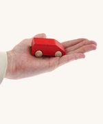 An adult hand holding the Beck wooden van toy in red available at Babipur showing scale