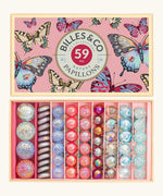 Billes & Co butterfly anamorphic glass marble set presented in a butterfly gift box. The marbles are lined up in order of size and pastel colours.