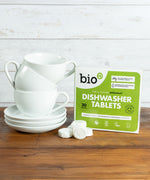 Bio-D dishwasher tablets opened and standing next to a stack of white mugs. These dishwasher tablets are available at Babipur.