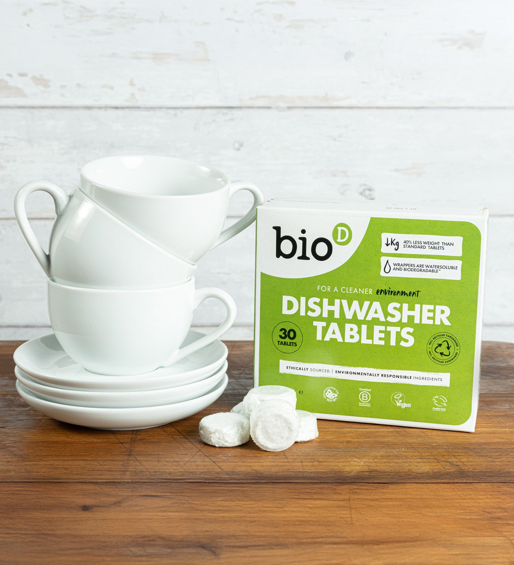 Bio-D dishwasher tablets opened and standing next to a stack of white mugs. These dishwasher tablets are available at Babipur.