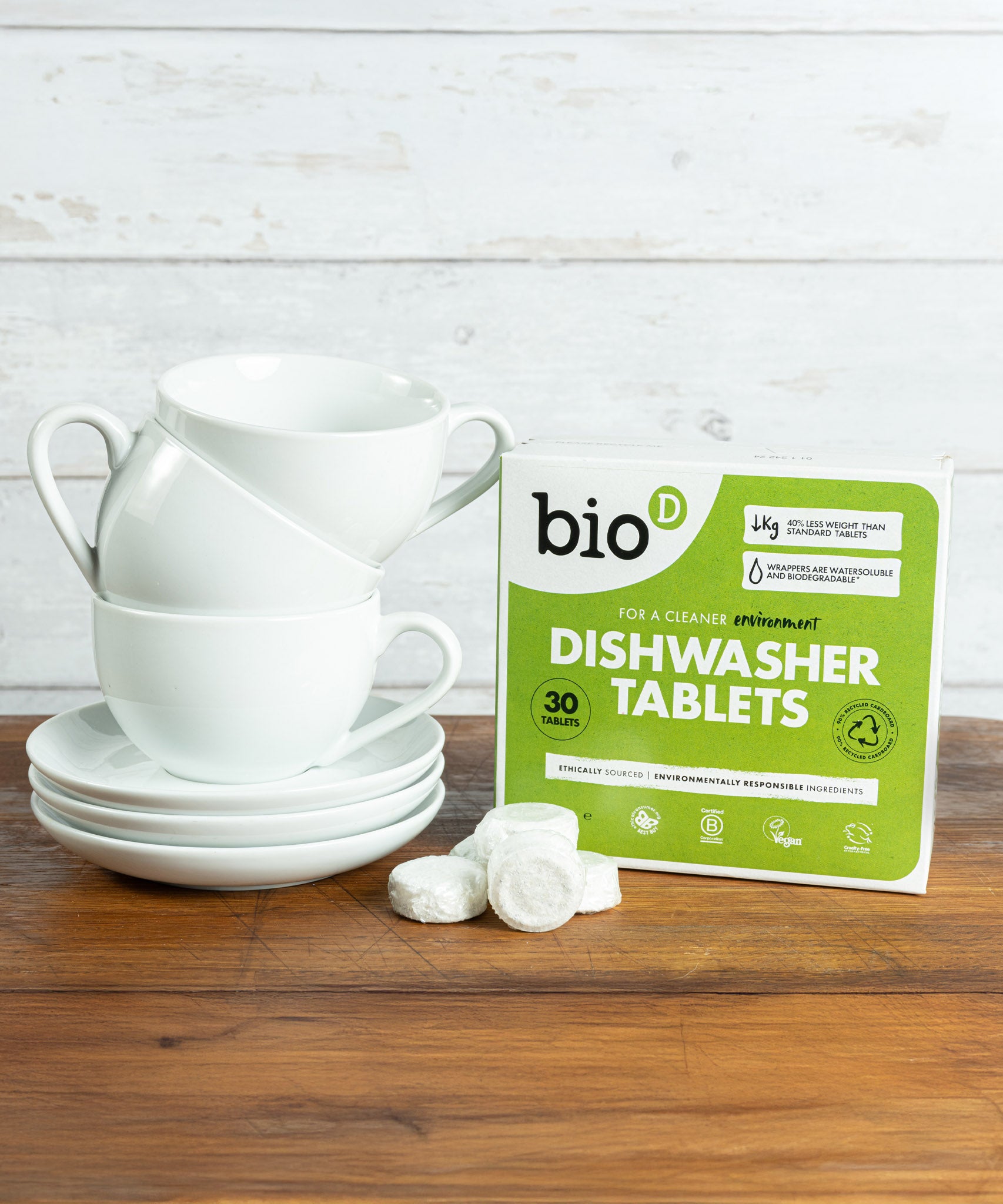 Bio-D dishwasher tablets opened and standing next to a stack of white mugs. These dishwasher tablets are available at Babipur.