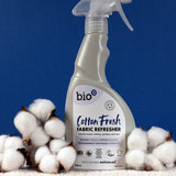 A 500ml spray bottle of Bio-D vegan and cruelty free cotton fresh fabric refresher standing on a blanket next to cotton 