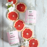 A flatlay image of 2 bottles of 500ml Bio-D cleansing hand wash  in geranium and grapefruit lined up next to slices of grapefruit. This hand wash is available at Babipur.